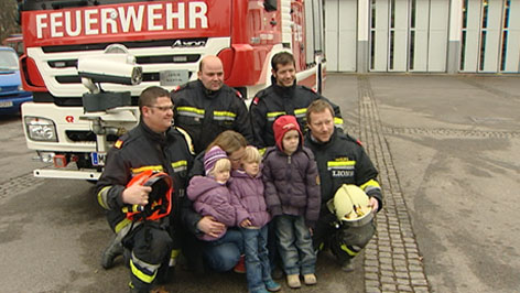 Feuerwehrleute mit Mutter und drei Kindern bei Fototermin