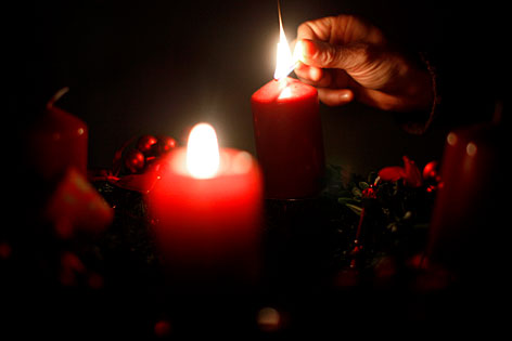 Kerzen auf Adventkranz werden angezündet