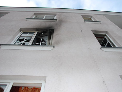 Fenster im ersten Stock mit Brandspuren und zerbrochenen Scheiben