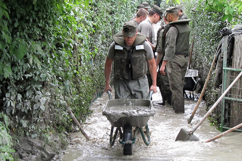 Soldaten des Bundesheeres räumen Schlamm in Schubkarren weg