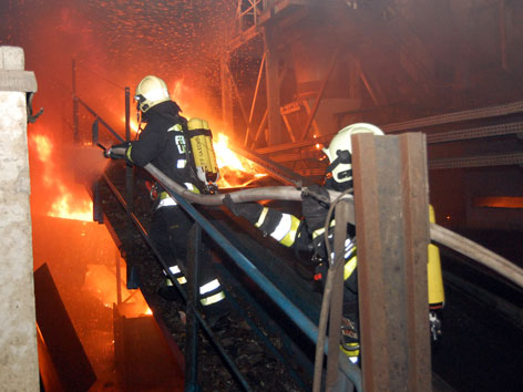 zwei Feuerwehrleute löschen Brand