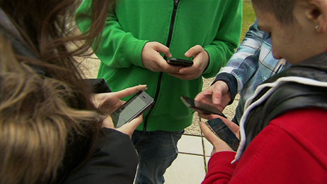 Jugendliche mit Handys stehen im Kreis