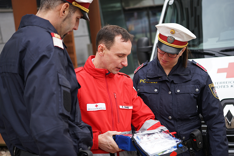 Sanitäter zeigt Polizisten Defibrillator